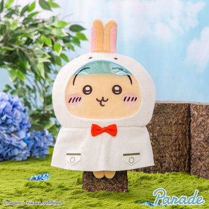 Cream hooded plush toy with teal inner hood and orange bow tie, smiling stitched face