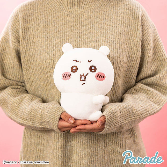 White plush toy with brown-red face and tiny paws, held in hands