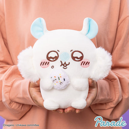 White plush toy with blue ears and brown face, held in hands with small squirrel plush