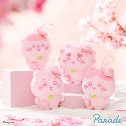 Pink plush mascot group with hanging loops and embroidered face, arranged on a display