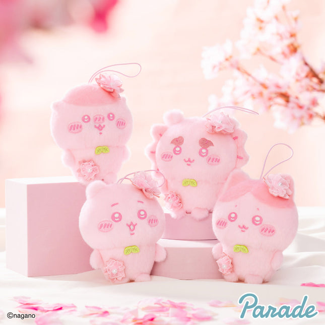 Pink plush mascot group with hanging loops and embroidered face, arranged on a display