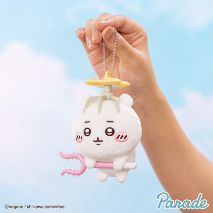 Plush mascot keychain held by hand, white character with pink arm prop and chain