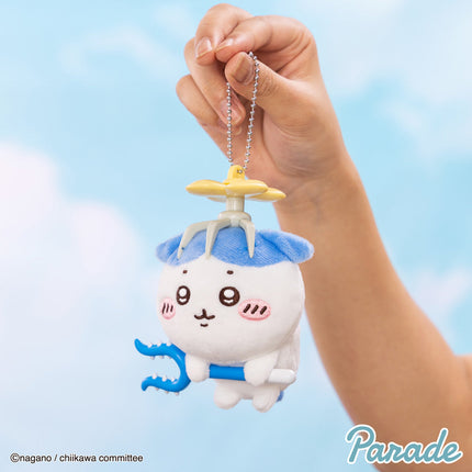 Plush mascot keychain held by hand, blue outfit character with blue arm prop and chain