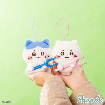 Two cream plush mascot keychains with blue and pink ear accents, holding colored toy bars