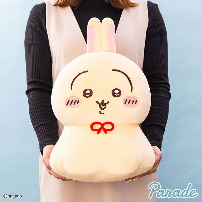 Cream bunny plush toy with pink ears and red bow, held in hands