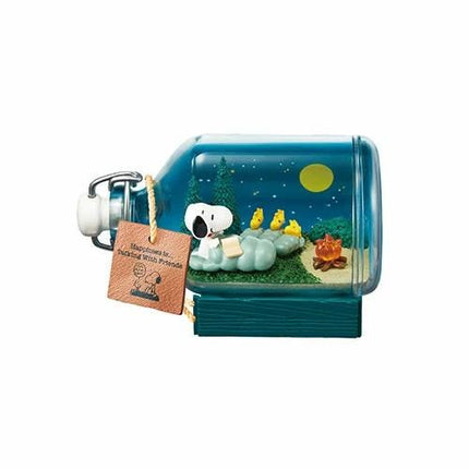 A bottle containing a miniature diorama depicting a nighttime scene with a cartoon character, likely a character from the Peanuts comic strip, in a forest setting.