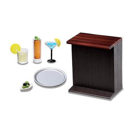 a variety of drinks and serving items, including two martini glasses, a cocktail glass, a lemon wedge, a plate, and a wooden bar stool.