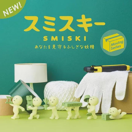a collection of small figurines, including a group of people and a cat, arranged on a green background. The figurines are depicted in a playful and whimsical manner, with some of them holding various objects such as a lamp, a pair of gloves, and a box. The image also includes text in Japanese, which translates to "SMISKI" and "MOVING SERIES", suggesting that the figurines are part of a series or collection related to the SMISKI brand.