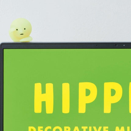 a small yellow figure sitting on top of a green screen displaying the word "HIPPIE" in large yellow letters.