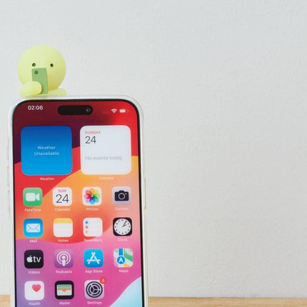 a smartphone with a colorful display and a small green figurine sitting on top of it.