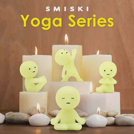 a collection of small, glowing yellow figurines arranged on a wooden surface, surrounded by lit candles and rocks.