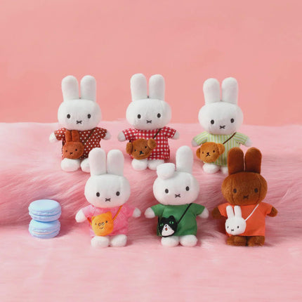May include: A collection of plush bunny dolls, each with a unique outfit and small companion. The bunnies are white with black eyes and a cross-shaped mouth. Outfits include polka dots, plaid, and solid colors. A few blue macarons are in the lower left.