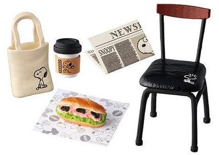 various items related to the character Snoopy, including a newspaper, a bag, a sandwich, a cup of coffee, and a chair.