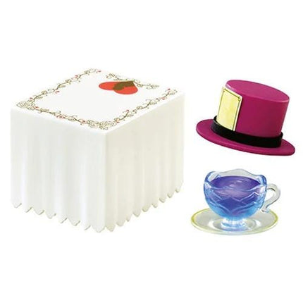 a square white cake with a red heart on top, a purple top hat, and a blue teacup on a saucer.