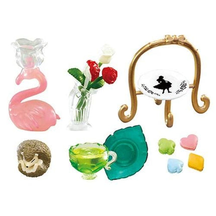 a variety of colorful and decorative items, including a pink flamingo, a vase with red roses, a gold stand, a green teapot, a brown bowl, and a collection of heart-shaped candies.