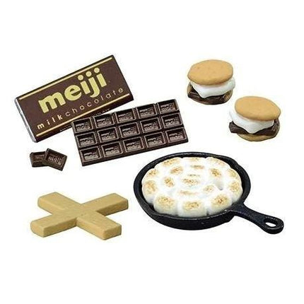 various food items, including a chocolate bar, two small sandwiches, a pan with a dessert, and a chocolate bar.