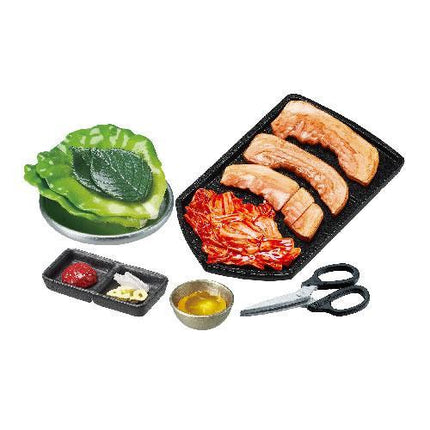 various food items and utensils, including a tray of sliced meat, a bowl of vegetables, a small bowl of sauce, and a pair of scissors.