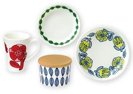 a collection of four ceramic items, including a white mug with a red flower design, a white plate with a blue and yellow floral design, a white bowl with a blue leaf pattern, and a white plate with a yellow flower design.