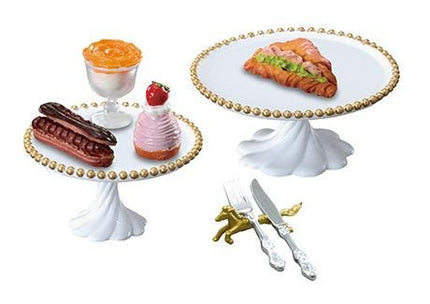 a variety of desserts and tableware, including a cake, a cupcake, a pastry, a donut, a bowl, a cake stand, a fork, a knife, and a spoon.