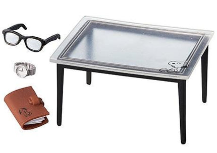 a table with a clear top, a pair of glasses, a watch, and a notebook.
