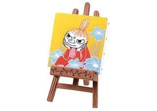 A small wooden easel with a painting of a cartoon character on it, set against a yellow background with blue flowers.