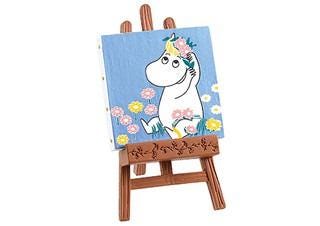 A small wooden easel with a painting of a cartoon character, specifically Moomoo, on it.