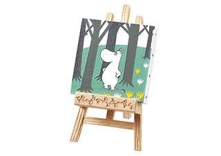 A small wooden easel displaying a painting of a white hippo standing in a forest with trees and flowers.
