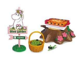 a toy set depicting a garden scene with a sign that reads "Olive garden" and a basket of fruit, including a small tree stump with pink flowers.