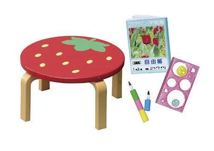 a red table with a green leaf design, a book with a picture of flowers, and some pens and a book.