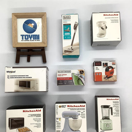 a collection of kitchen appliances and accessories, including a framed logo, a vacuum cleaner, a blender, and various boxes of kitchenaid products.