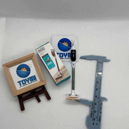 various objects, including a ruler, a box, a pen, and a picture frame, all placed on a white surface.