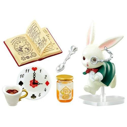A figurine of a rabbit wearing a green cape and glasses, holding a book, a clock, a jar of honey, and a cup of tea.