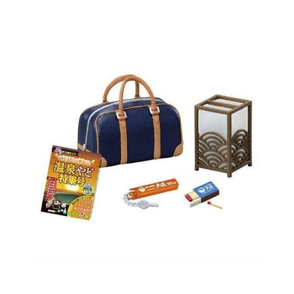 a blue handbag, a book, a keychain, a matchbox, and a small lamp.