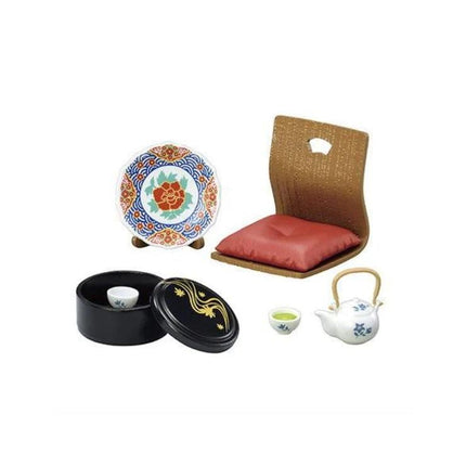 various ceramic items, including a plate, a teapot, a small bowl, and a small cup, all arranged on a white background.
