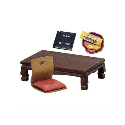 a traditional Japanese dining setting, including a low wooden table with a red cushion, a brown folding chair, and a small plate with snacks.