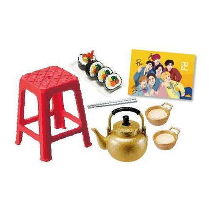 a red plastic stool, sushi, a teapot, cups, and a card with cartoon characters on it.