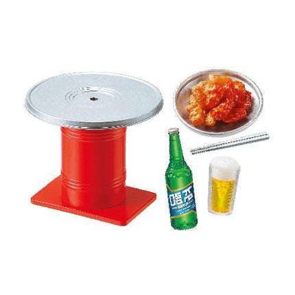a red table, a plate of food, a green bottle, and a glass of beer.