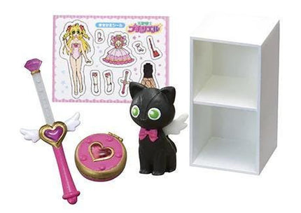 a black cat figurine, a pink and gold wand, a pink and gold heart-shaped charm, and a white shelf.