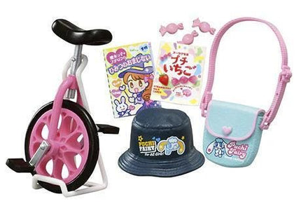 a variety of toys and items, including a pink and black bicycle, a black hat, a blue purse, and some candy.