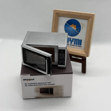 a small microwave oven placed on a white surface, with a framed picture of a microwave oven in the background.