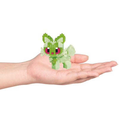 A hand holding a small green pixelated character, likely a pixel art or LEGO-like figure.