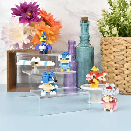 a collection of colorful pixel art toys, including a blue bird, a pink and yellow fish, and a blue and white robot, arranged on a shelf or display.