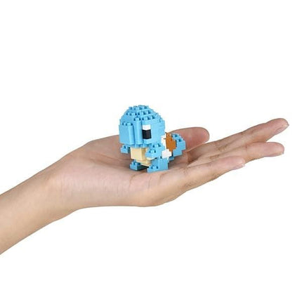 A hand holding a small blue and white pixelated character, likely a pixel art or block toy.