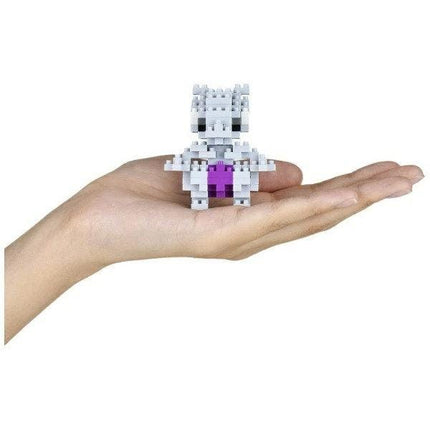 A hand holding a small, white and purple cube-shaped object.