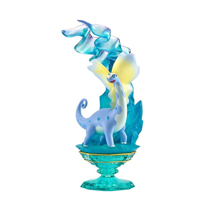 A figurine of a blue dinosaur-like creature with a yellow head and wings, standing on a green base.