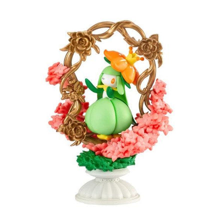 A figurine of a green frog wearing a crown, surrounded by a decorative floral frame and pink flowers.