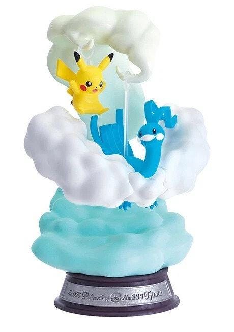 A figurine of Pikachu and Quicksilver, two popular Pokémon characters, are depicted in a whimsical scene with clouds and a rainbow.