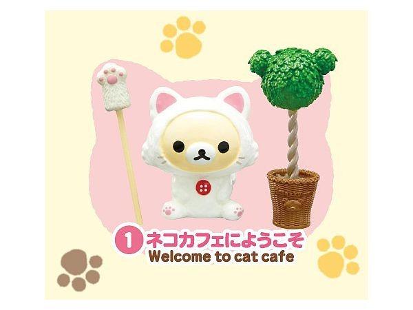 A small white cat figurine with a red button on its chest, surrounded by a cat-themed background with paw prints and a tree-shaped object.