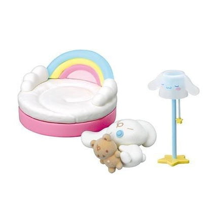 A collection of colorful toys, including a rainbow-colored bed, a teddy bear, and a lamp with a white hat, arranged on a white background.