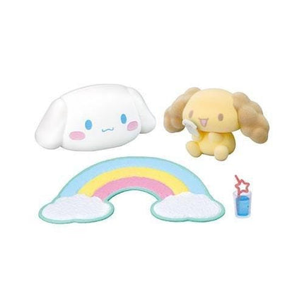 a variety of colorful plush toys, including a white plush toy resembling a smiling face, a yellow plush toy resembling a dog, and a rainbow-colored plush toy. There is also a small glass with a blue liquid and a star-shaped plush toy.